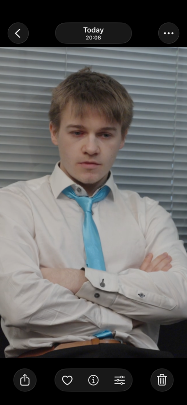 Andy Grant Young man in a white shirt and blue tie sitting with arms crossed, looking serious.